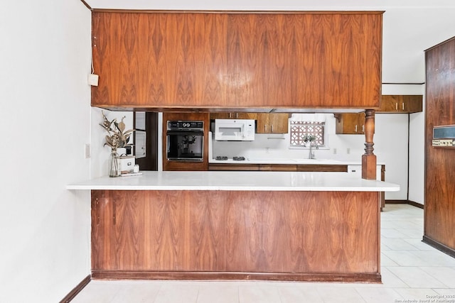 kitchen featuring light tile patterned flooring, sink, kitchen peninsula, and oven