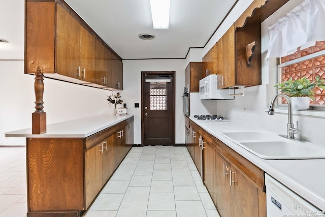 kitchen with white appliances, light tile patterned floors, and sink