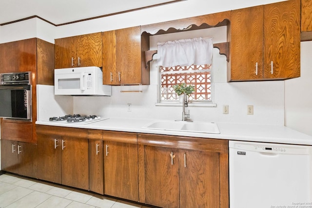 kitchen with sink, white appliances, and light tile patterned flooring