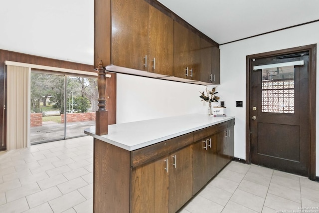 kitchen with light tile patterned floors, wood walls, and dark brown cabinetry