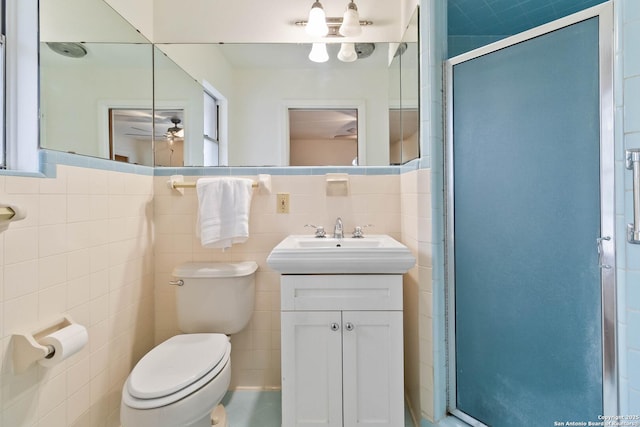 bathroom with toilet, vanity, tile walls, ceiling fan, and an enclosed shower