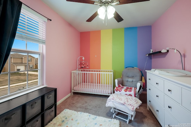 bedroom with ceiling fan, light colored carpet, and a nursery area