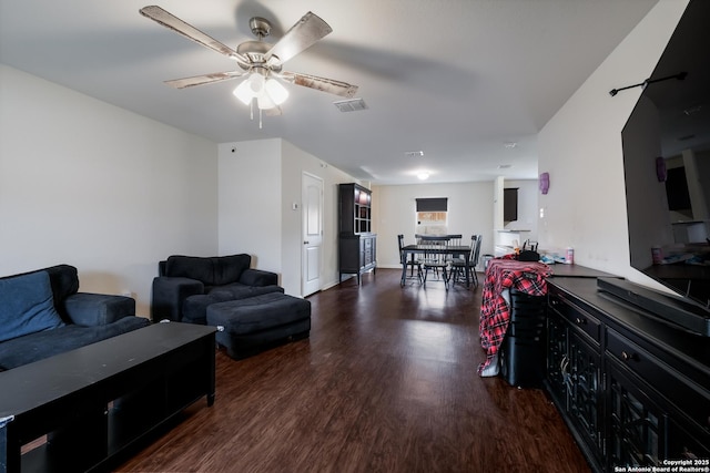 living room featuring ceiling fan and dark wood-type flooring