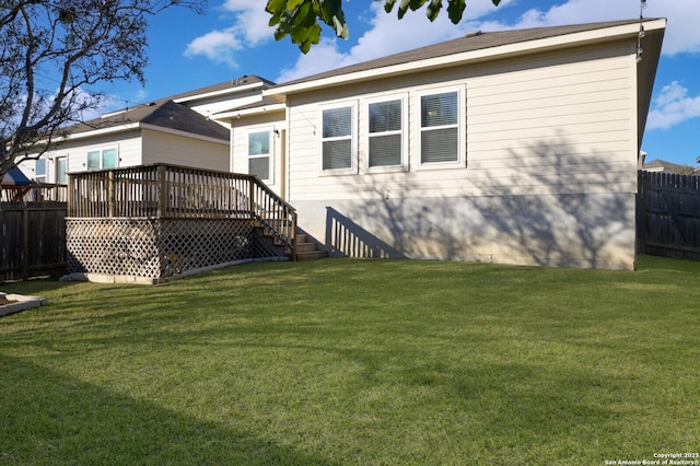 rear view of house with a lawn and a wooden deck