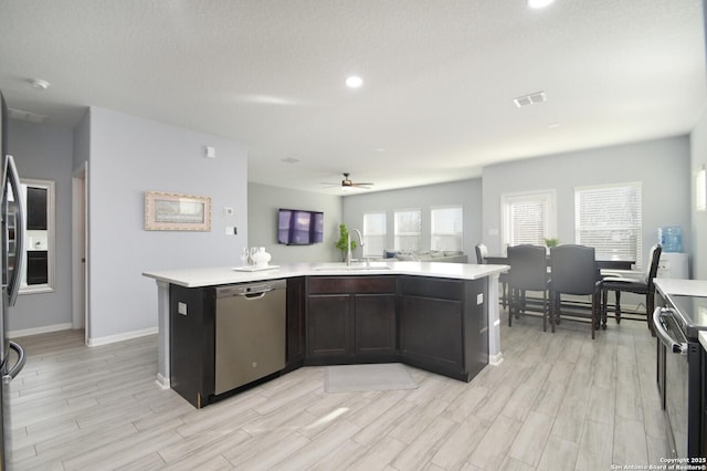 kitchen with ceiling fan, appliances with stainless steel finishes, an island with sink, and sink