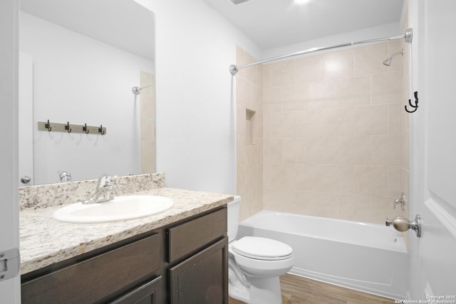 full bathroom with toilet, tiled shower / bath combo, wood-type flooring, and vanity