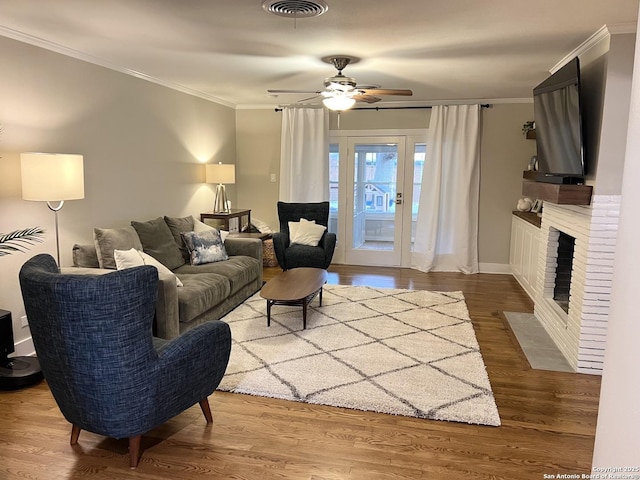 living room with ceiling fan, a fireplace, ornamental molding, and hardwood / wood-style floors