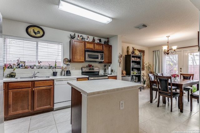 kitchen with a center island, pendant lighting, appliances with stainless steel finishes, a textured ceiling, and a chandelier