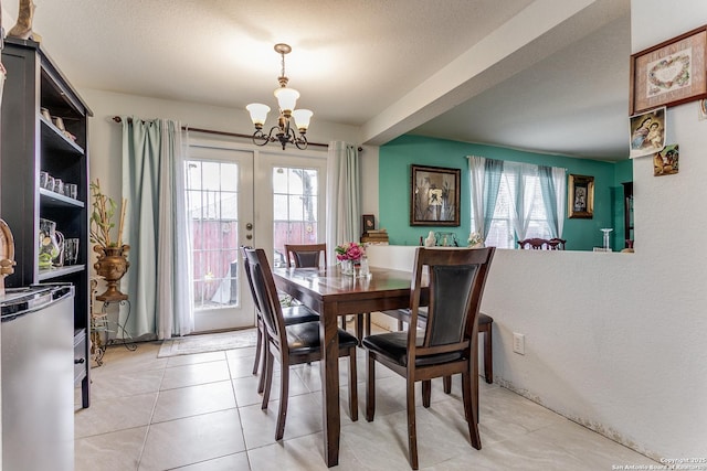 dining space featuring french doors, light tile patterned floors, a textured ceiling, and a notable chandelier