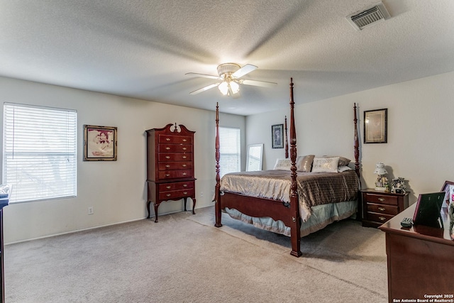 bedroom with ceiling fan, a textured ceiling, and light carpet