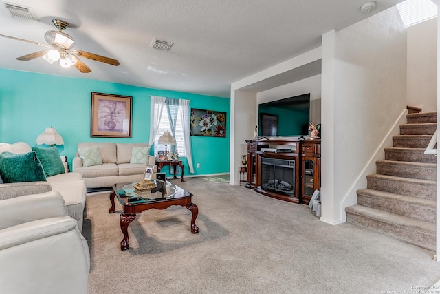 living room featuring ceiling fan, carpet, and a textured ceiling