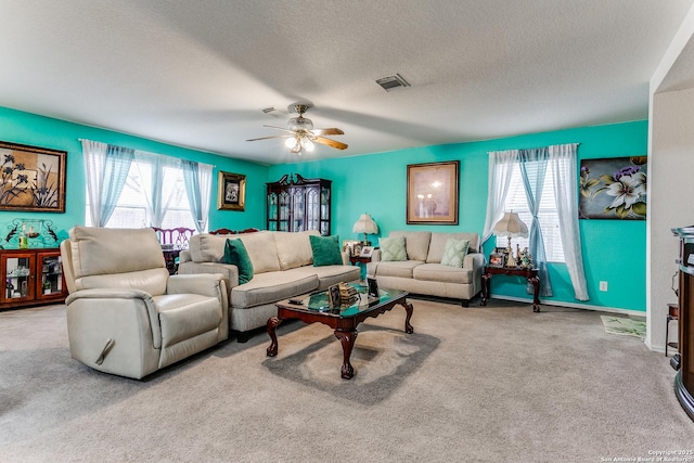 living room featuring ceiling fan, light colored carpet, plenty of natural light, and a textured ceiling