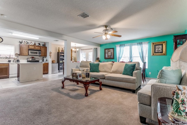 carpeted living room with ceiling fan with notable chandelier and a textured ceiling