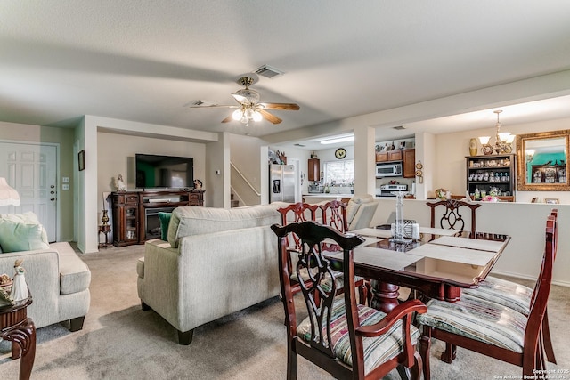 carpeted dining space featuring ceiling fan with notable chandelier