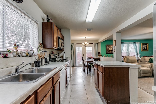 kitchen with light tile patterned floors, stainless steel appliances, a chandelier, pendant lighting, and sink