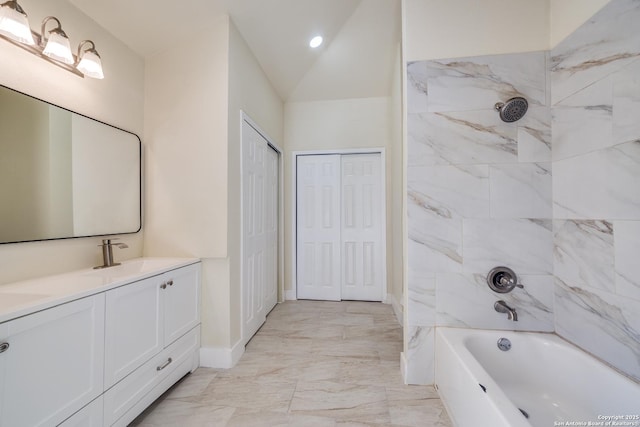 bathroom featuring vanity, vaulted ceiling, and tiled shower / bath