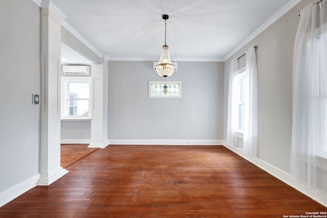 spare room with a wall unit AC, hardwood / wood-style floors, ornamental molding, and a chandelier