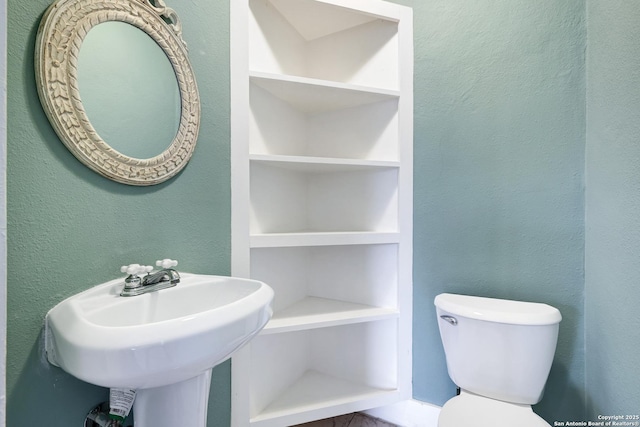 bathroom featuring sink, toilet, and built in features