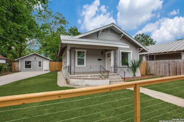 bungalow-style home with covered porch, a front lawn, and an outbuilding