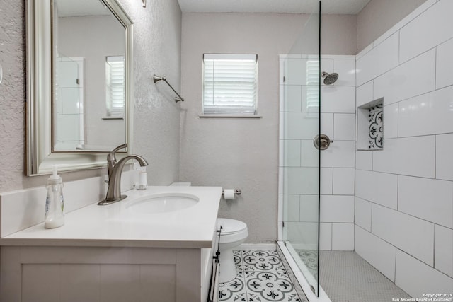 bathroom featuring toilet, vanity, tile patterned floors, and a tile shower