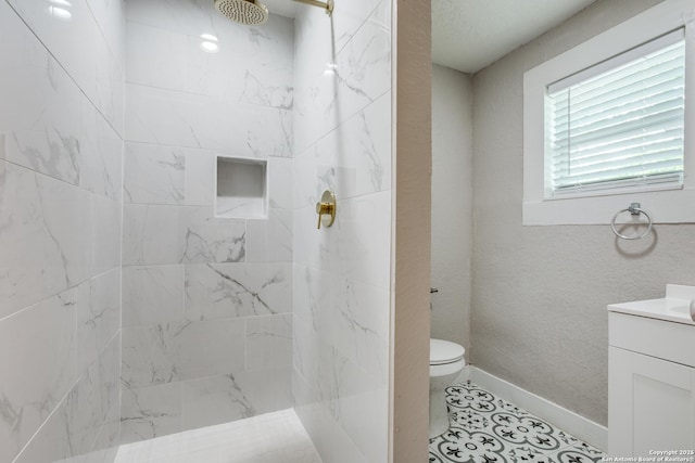 bathroom featuring tile patterned floors, toilet, vanity, and a tile shower