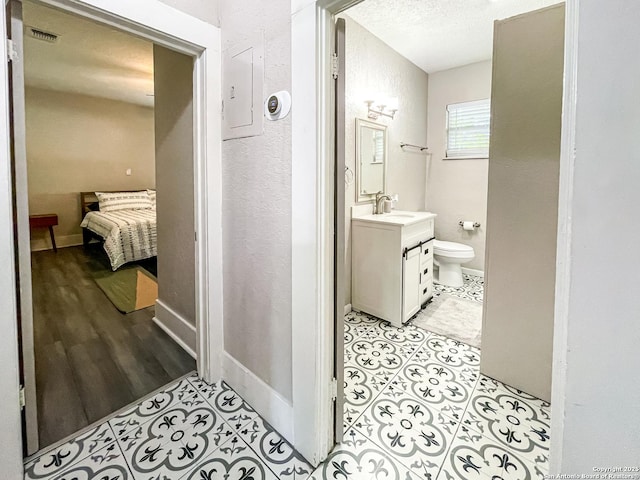 bathroom featuring toilet, hardwood / wood-style floors, a textured ceiling, electric panel, and vanity