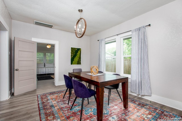 dining space featuring hardwood / wood-style flooring, a textured ceiling, and a chandelier