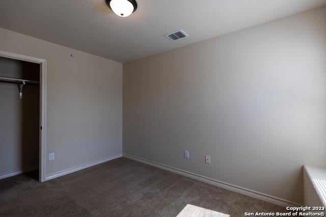 unfurnished bedroom with a closet and dark colored carpet