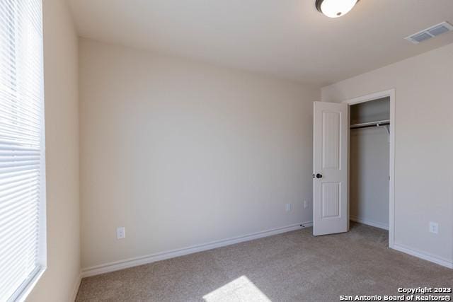 unfurnished bedroom featuring light carpet and a closet