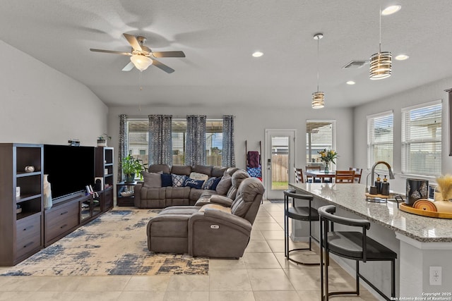 tiled living room featuring ceiling fan, vaulted ceiling, and a textured ceiling