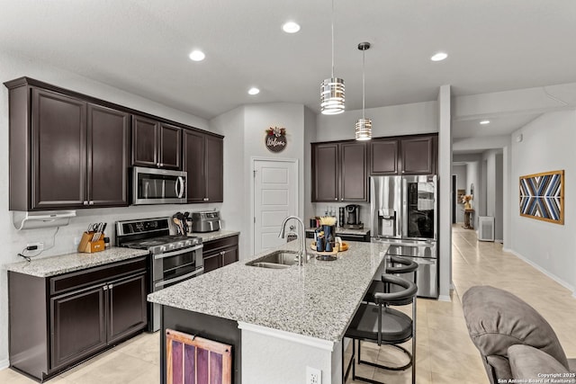 kitchen featuring pendant lighting, a kitchen bar, sink, an island with sink, and stainless steel appliances