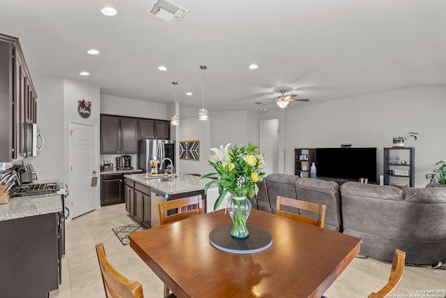 dining space with ceiling fan, light tile patterned floors, vaulted ceiling, and sink