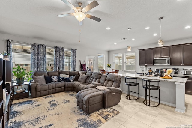 tiled living room with ceiling fan, sink, and a textured ceiling