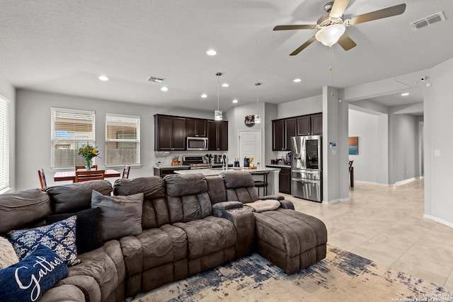 living room with ceiling fan and a textured ceiling