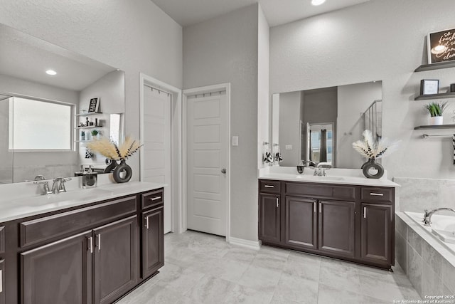 bathroom with tiled tub and vanity