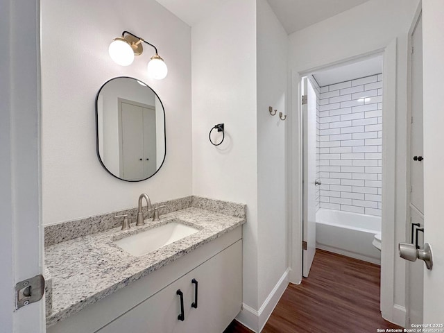 bathroom with wood-type flooring, vanity, and tiled shower / bath