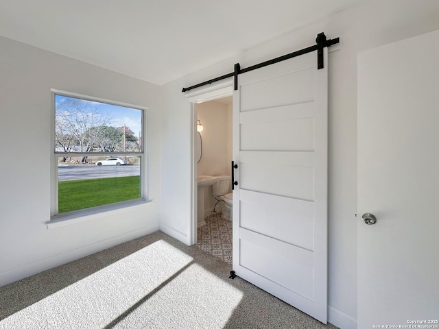 interior space featuring carpet, ensuite bathroom, and a barn door