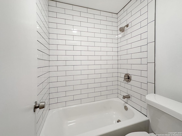 bathroom with toilet and tiled shower / bath