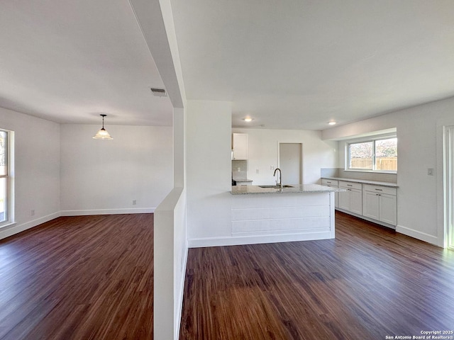 kitchen with dark wood-type flooring, white cabinets, light stone counters, and decorative light fixtures