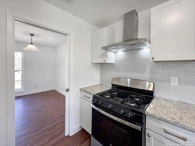 kitchen featuring pendant lighting, wall chimney exhaust hood, white cabinetry, backsplash, and gas range oven