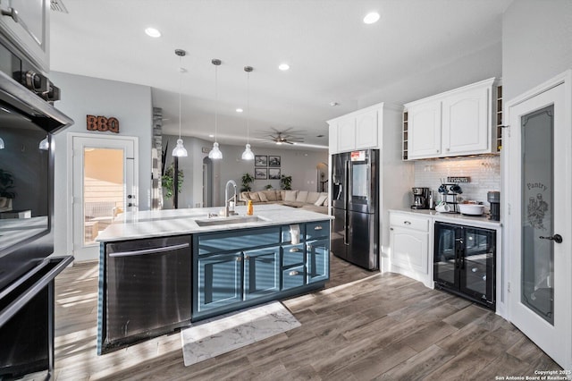 kitchen with stainless steel fridge, wine cooler, pendant lighting, white cabinets, and sink