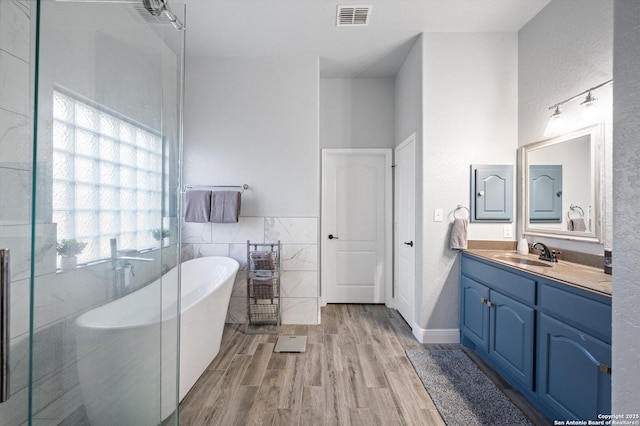 bathroom featuring a tub, vanity, tile walls, and hardwood / wood-style floors