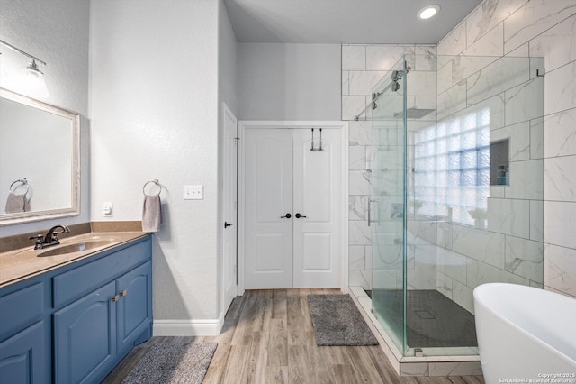 bathroom with plus walk in shower, wood-type flooring, and vanity