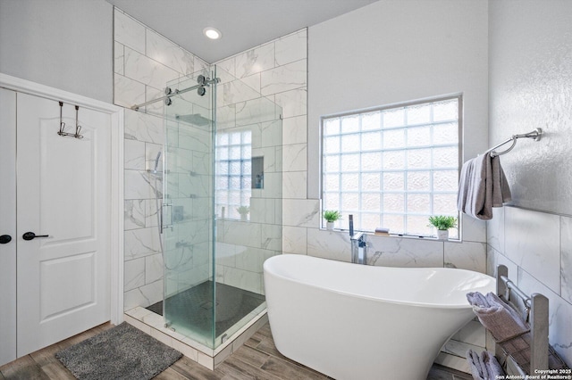 bathroom with a wealth of natural light, tile walls, and independent shower and bath