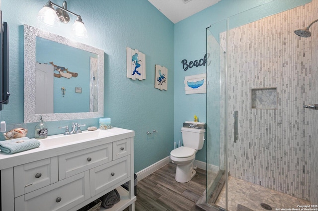 bathroom with toilet, vanity, wood-type flooring, and an enclosed shower