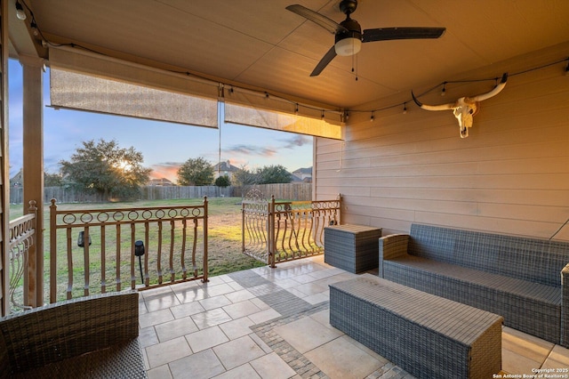 patio terrace at dusk with ceiling fan and an outdoor living space