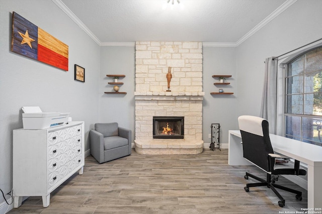 home office with crown molding, a stone fireplace, a textured ceiling, and light hardwood / wood-style flooring