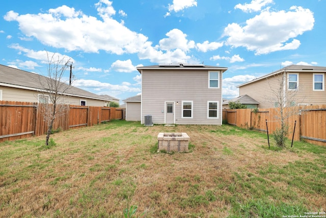 rear view of house featuring an outdoor fire pit, a yard, solar panels, and central air condition unit