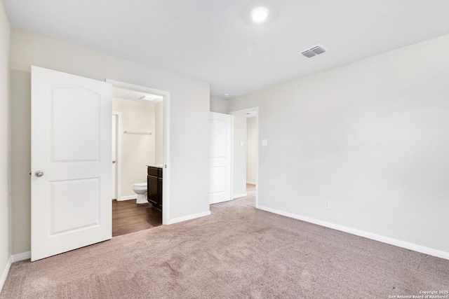 unfurnished bedroom featuring ensuite bathroom and carpet floors