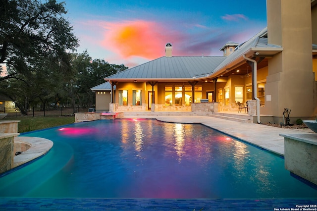 pool at dusk with a patio area and ceiling fan